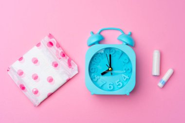 Mavi çalar saat, kadın hijyenik ped ve tampon, üst manzara.