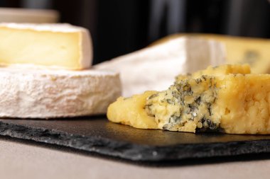 Siyah, düz tabakta servis edilen bir sürü peynir.