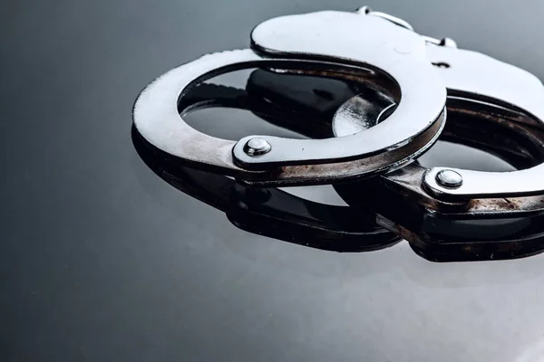 Metal closed handcuffs on black background with reflection — Stock Photo, Image