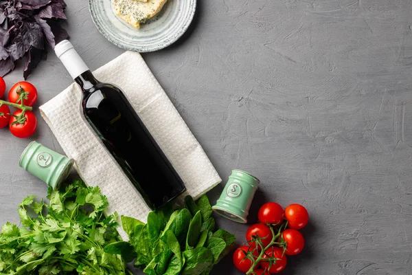 Butelka czerwonego wina na szarej powierzchni z warzywami — Zdjęcie stockowe