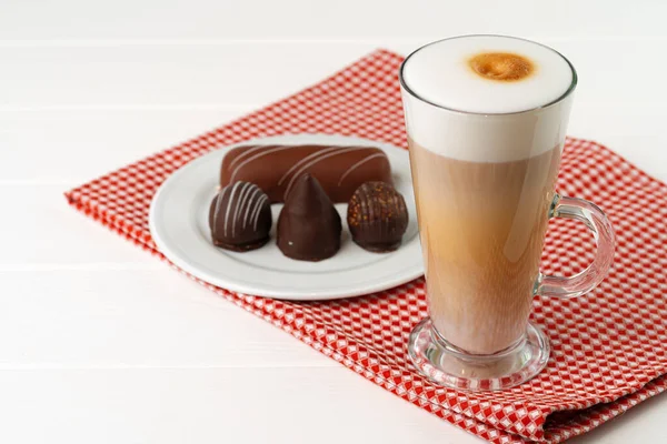 Kopje koffie en schotel met chocolade snoepjes op houten tafel — Stockfoto