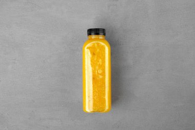 Gri arka planda taze sıkılmış portakal suyu şişesi