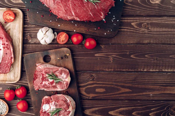 Surowe kawałki mięsa wołowego na brązowej drewnianej desce — Zdjęcie stockowe