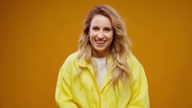 Sarı arka planda gülümseyen mutlu genç kadın portresi