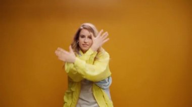 Stüdyoda sarı arka planda dans eden profesyonel kadın dansçı.