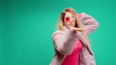 Pembe elbiseli zarif genç bir kadın, darphane arka planına karşı ritim tutuyor.