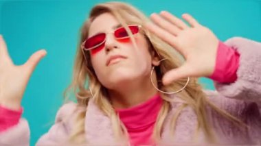 Pembe elbiseli zarif genç bir kadın, darphane arka planına karşı ritim tutuyor.