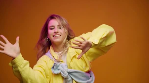 Trendige junge Frau tanzt vor gelbem Hintergrund — Stockvideo