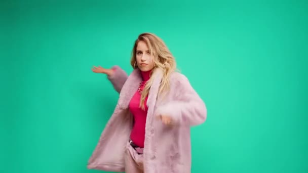 Elegante mujer joven en rosa moviéndose hacia el ritmo contra fondo de menta — Vídeo de stock