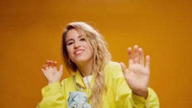 Stüdyoda sarı arka planda dans eden profesyonel kadın dansçı.