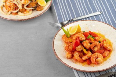 Tabakta peçeteyle soslu kızarmış deniz ürünleri karıştır.