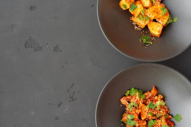 Fıstıklı kızarmış tavuk ve gri arka plandaki kaselerde kızarmış patlıcan.