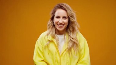 Sarı arka planda gülümseyen mutlu genç kadın portresi