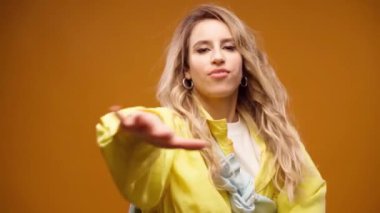 Stüdyoda sarı arka planda dans eden profesyonel kadın dansçı.