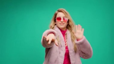 Pembe elbiseli zarif genç bir kadın, darphane arka planına karşı ritim tutuyor.