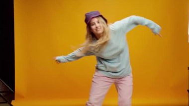 Sarı arka planda dans eden Panama şapkalı mutlu genç kadın.