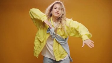 Stüdyoda sarı arka planda dans eden profesyonel kadın dansçı.