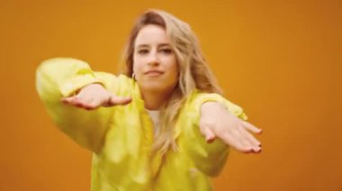 Stüdyoda sarı arka planda dans eden profesyonel kadın dansçı.