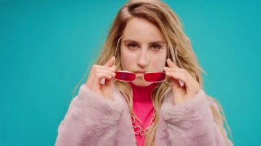 Pembe elbiseli zarif genç bir kadın, darphane arka planına karşı ritim tutuyor.