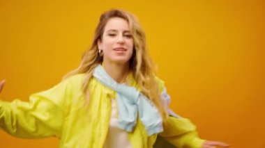 Stüdyoda sarı arka planda dans eden profesyonel kadın dansçı.