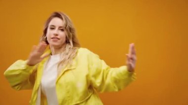 Stüdyoda sarı arka planda dans eden profesyonel kadın dansçı.