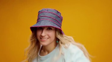 Sarı arka planda dans eden Panama şapkalı mutlu genç kadın.