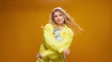 Stüdyoda sarı arka planda dans eden profesyonel kadın dansçı.