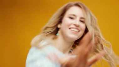 Stüdyoda sarı arka planda dans eden profesyonel kadın dansçı.