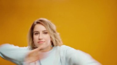 Stüdyoda sarı arka planda dans eden profesyonel kadın dansçı.