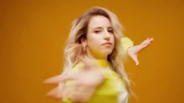 Stüdyoda sarı arka planda dans eden profesyonel kadın dansçı.