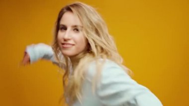 Stüdyoda sarı arka planda dans eden profesyonel kadın dansçı.