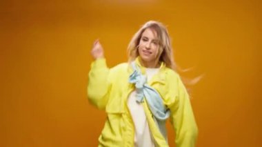 Stüdyoda sarı arka planda dans eden profesyonel kadın dansçı.