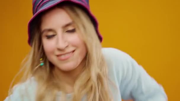 Молода щаслива жінка в панамському капелюсі танцює на жовтому фоні — стокове відео