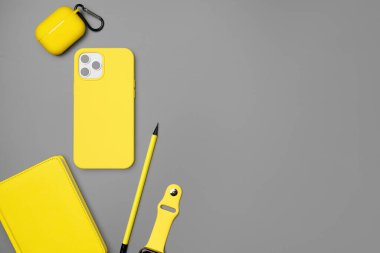 Sarı not defteri, akıllı telefon ve gri arka planda kulaklık.