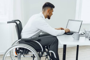 Dizüstü bilgisayar kullanarak tekerlekli sandalyedeki engelli adam