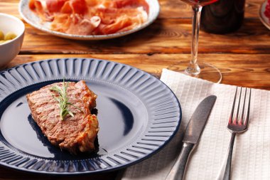 Mavi tabakta servis edilen ızgara biftek.