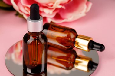 Pembe arka planda yuvarlak aynada yağlı cam şişe.