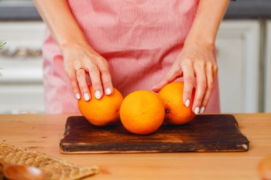 Mutfakta dikilirken elinde portakal tutan tanınmayan bir kadın.