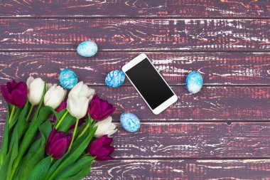 Paskalya, bayram, gelenek ve nesne konsepti - renkli paskalya yumurtaları, lale çiçekleri ve akıllı telefonlara yakın çekim