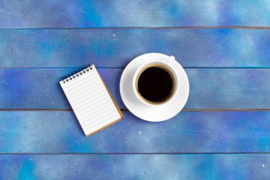 Kontrol listesi için model, mavi ahşap arka planda kahve fincanı olan boş not kağıdı. Ofis, yazar veya öğrenim kavramı