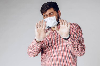 Koruyucu tıbbi maske ve eldiven takmış korkmuş bir adamın portresi..