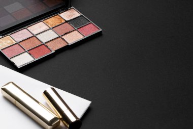 Siyah doku arka planında çeşitli makyaj ürünleri.