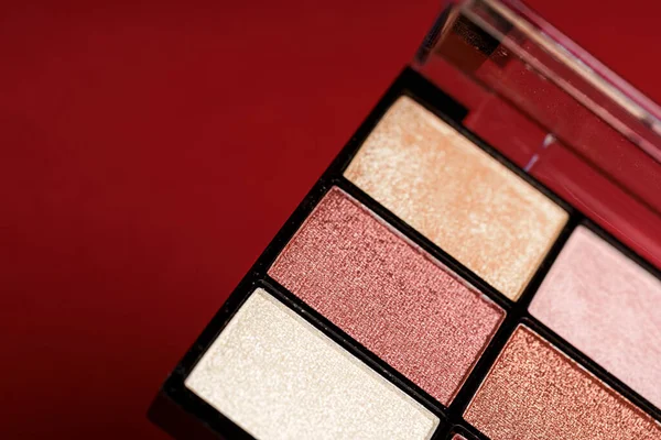 Makeup eyeshadow palette on the red background.