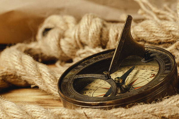 Судовой канат и компас на деревянном фоне