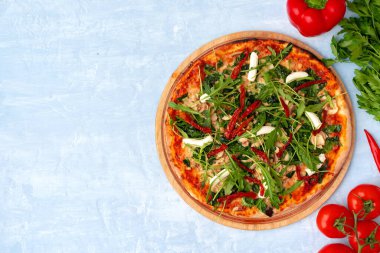 Bitkilerle taze pizza ve gri masada kurutulmuş domatesler.