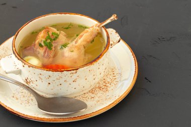 Tavuk suyu, yarısı beyaz kâsede, gri arka planda.