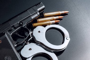 Siyah arka planda kelepçe ve tüfek fişekleri.