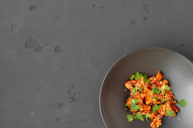 Siyah seramik kasede soslu kızarmış tavuk ve fıstık.