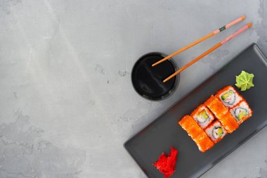 Kaliforniya suşi rulosu gri arka planda servis edilir