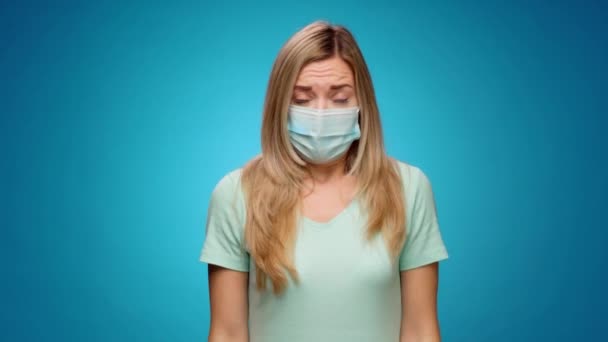 Jonge vrouw in medisch masker strekken handen, stoppen met gebaar tegen blauwe abckground — Stockvideo